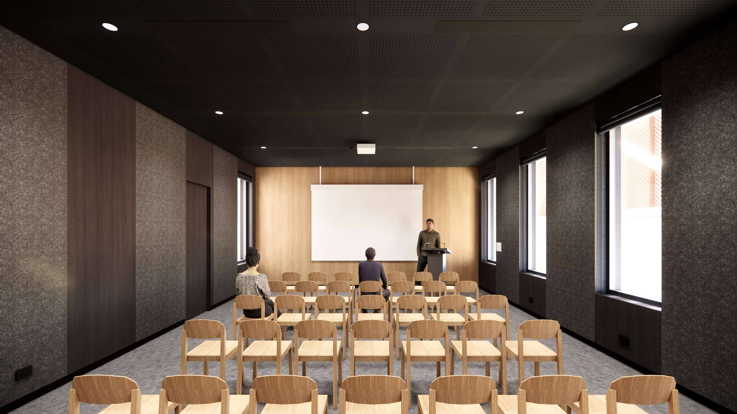 Modern conference room with wooden chairs, two attendees seated, and a speaker at a podium in front of a blank projection screen.