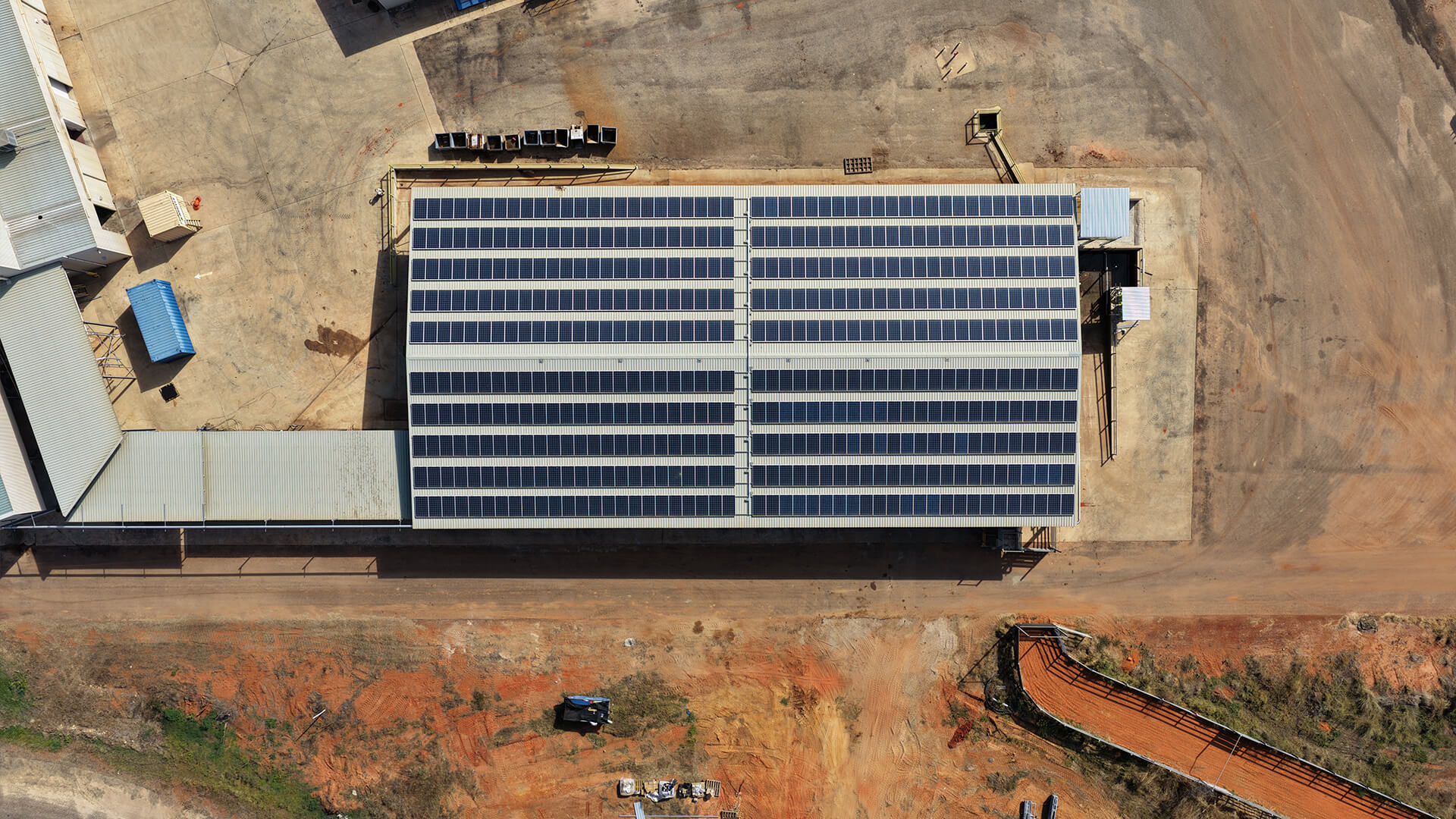 Aerial view of solar panels covering the roof of an industrial building on dry land.